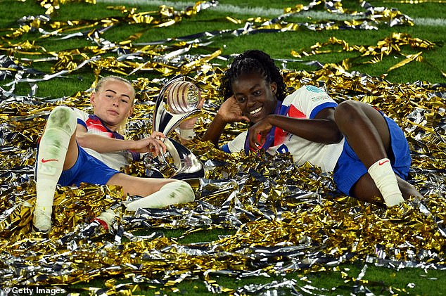 Chloe Kelly and Michelle Agyemang of England celebrate with the Euros trophy while laying in ticker tape