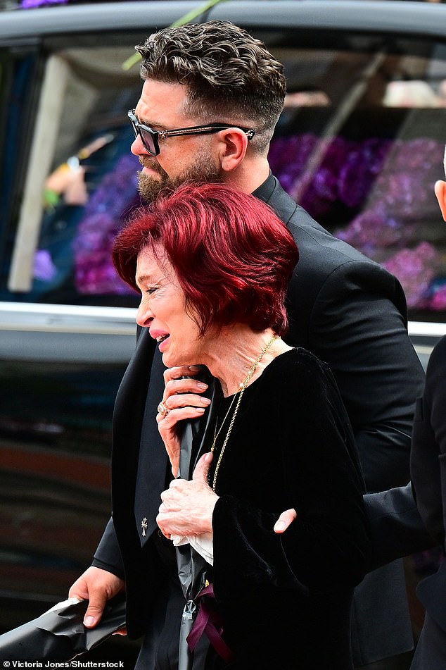 Sharon leans on her son Jack for support as she clutches on to a bouquet of flowers