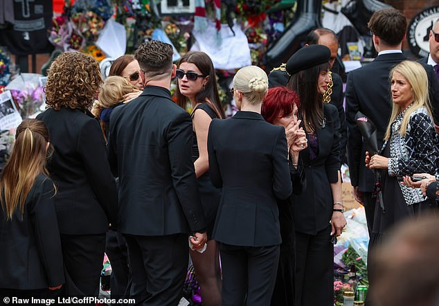 Ozzy Osbourne's family members stand among the crowd as Ozzy's funeral procession makes its way through Birmingham