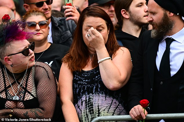 An emotional fan watches as Ozzy Osbourne's funeral procession makes its way through Birmingham