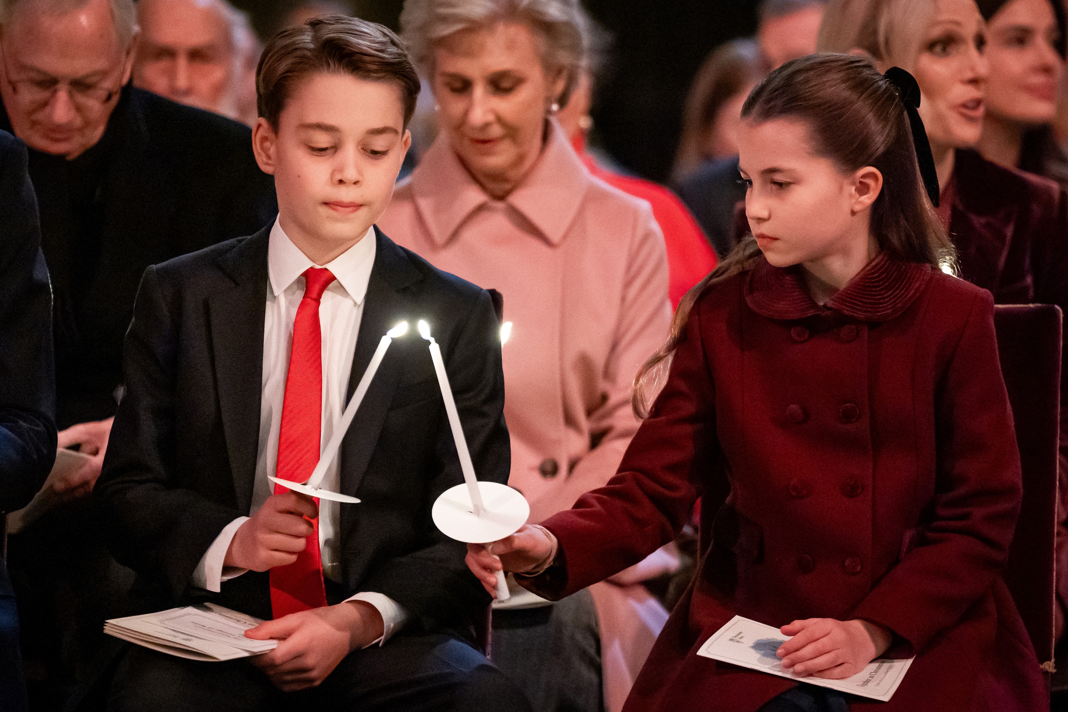 Princess Charlotte and Prince George sitting in church lighting each other's candles