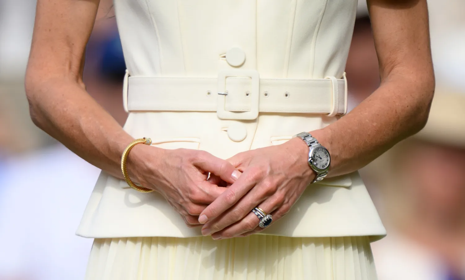 Closeup of Kate Middleton's hands folded in front wearing a formal outfit with a belt and accessories