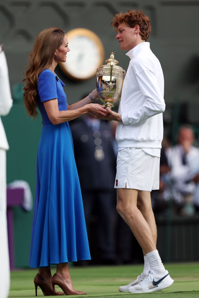 Catherine, Princess of Wales, presents a Wimbledon tennis trophy to a male player.