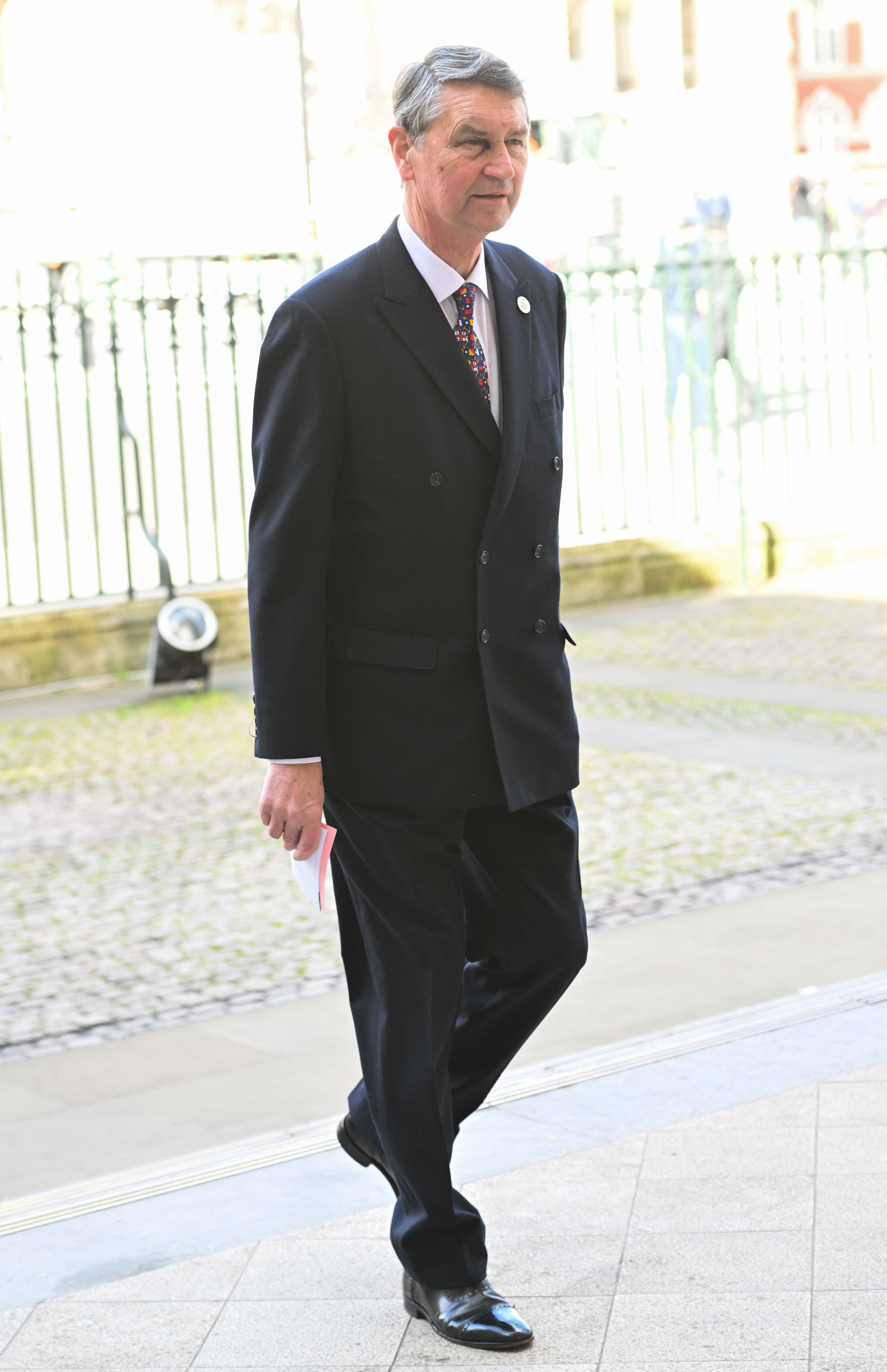 Sir Timothy laurence in a black suit walking