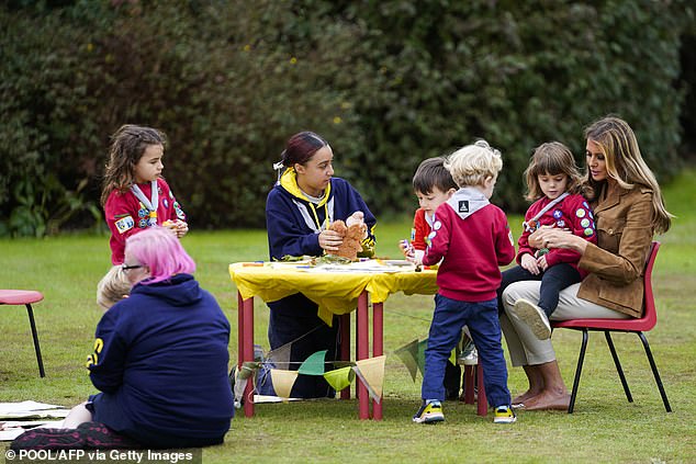 Melania sat at a crafts table with members of the Squirrel Scouts and their leaders, with one little girl sitting on the First Lady's knee