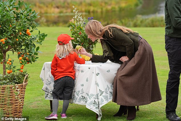 Kate stopped to offer one of the young children a piece of fruit which might have come from one of the trees on the estate