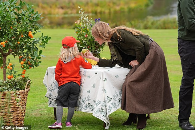 Kate stopped to offer one of the young children a piece of fruit which might have come from one of the trees on the estate