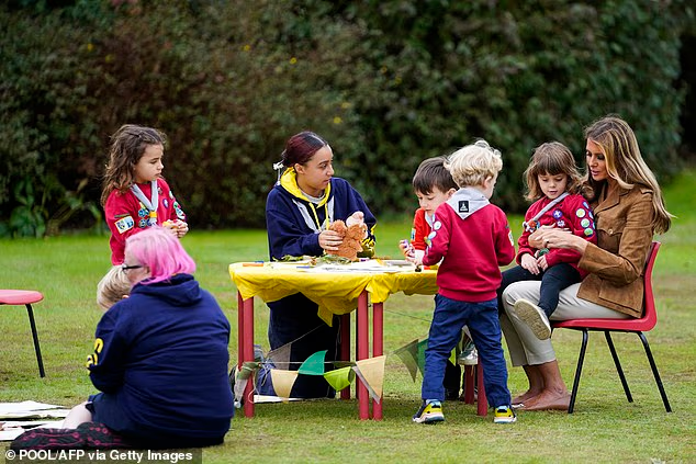Melania sat at a crafts table with members of the Squirrel Scouts and their leaders, with one little girl sitting on the First Lady's knee