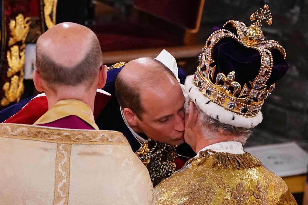 Prince William, Prince of Wales kisses his father, Britain's King Charles III, wearing St Edward's Crown, during the King's Coronation Ceremony