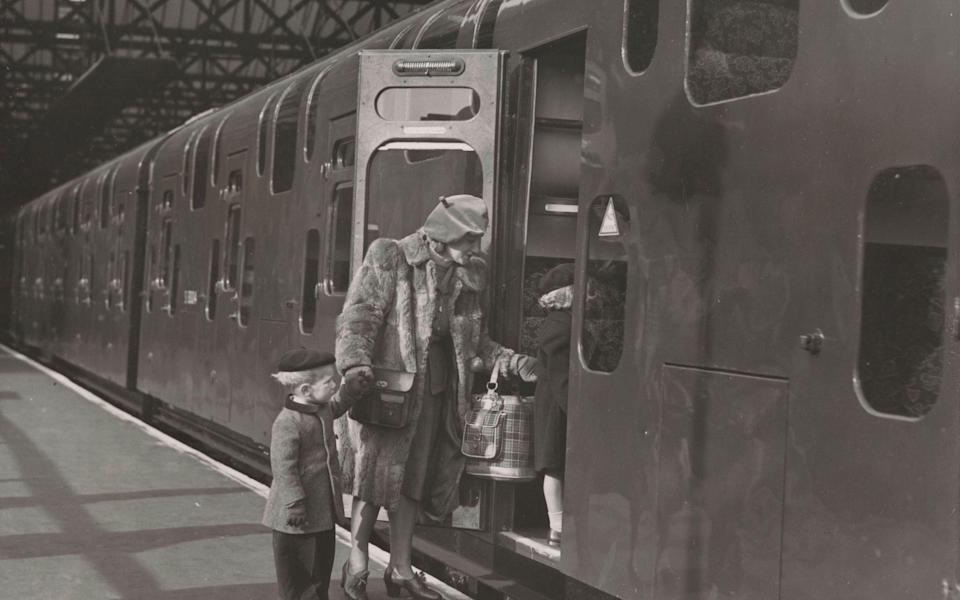 Woman and two children board a double-decker train at Charing Cross Station in London, 1949