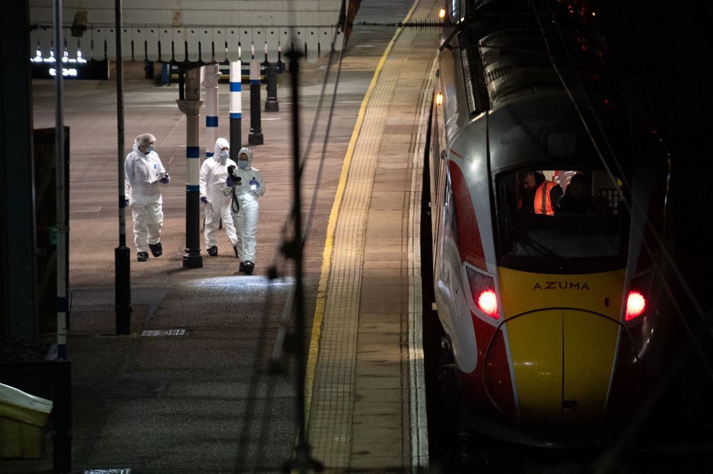 Crime scene investigators walk along a train platform at Huntingdon Station on 2 November