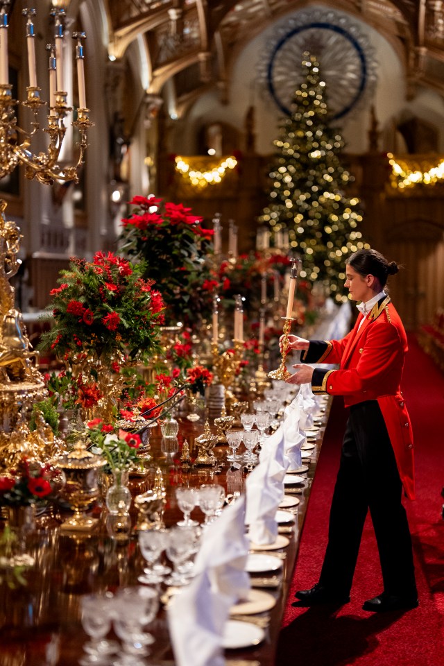 Royal Household staff member placing a candle on a long dining table at Windsor Castle during state banquet preparations.