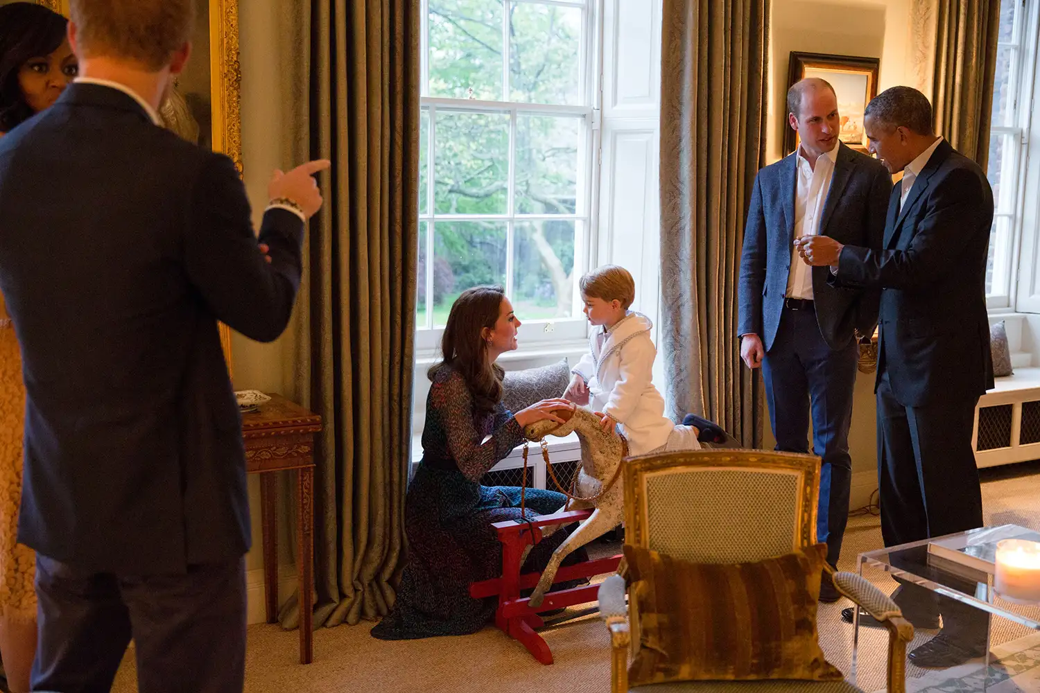 President Barack Obama talks with the Prince William, Duke of Cambridge as Catherine, Duchess of Cambridge plays with Prince George as First Lady Michelle Obama talks with Prince Henry at Kensington Palace