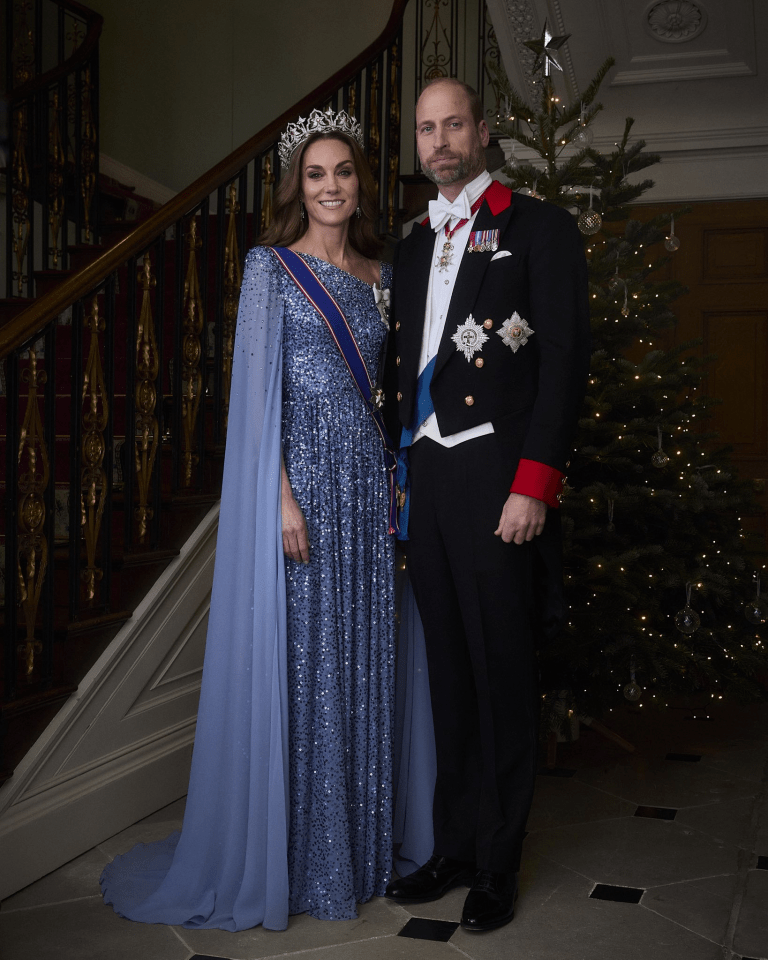 The Prince and Princess of Wales standing by a staircase and Christmas tree.