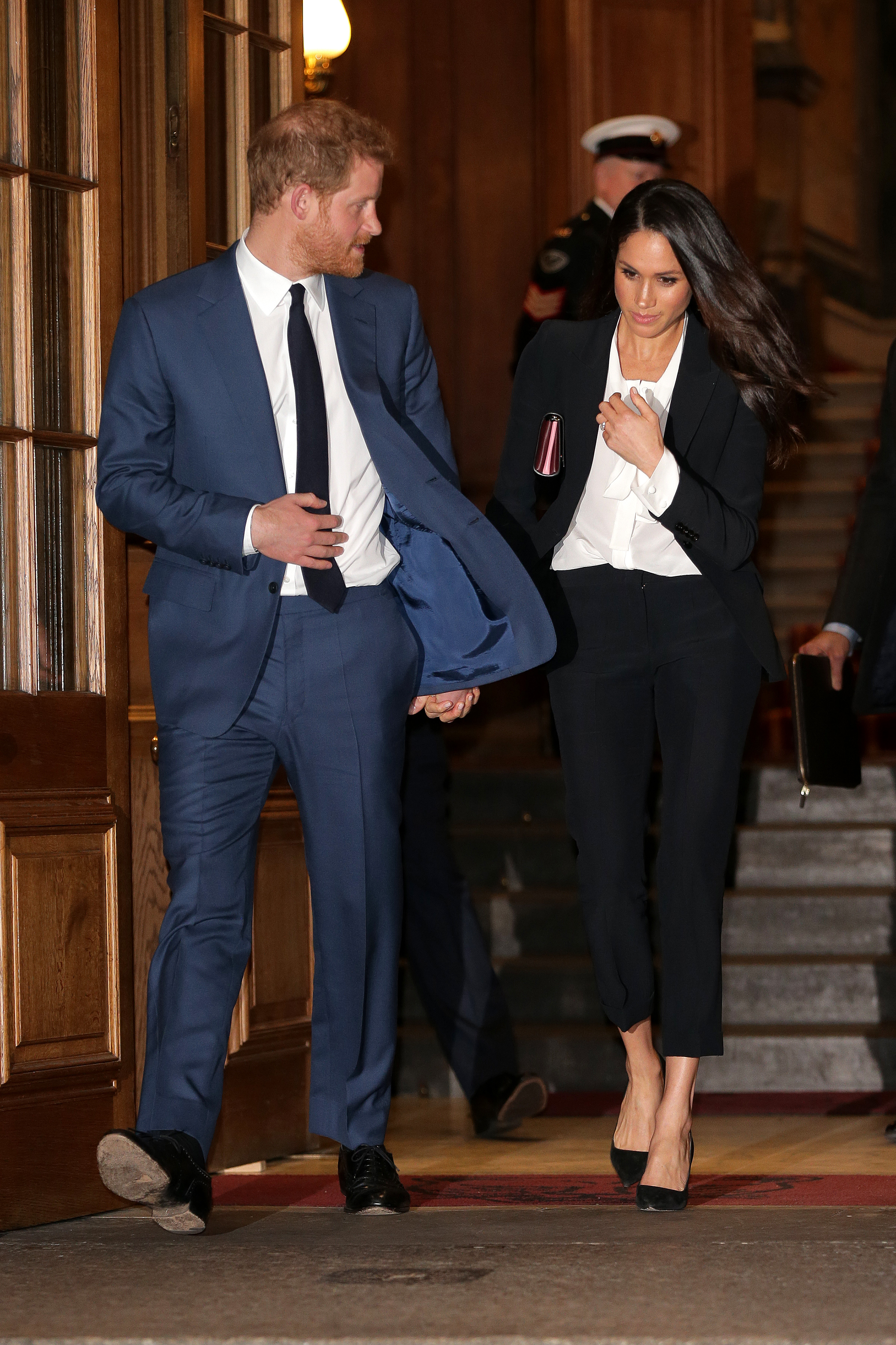 Prince Harry and Meghan Markle entering an event, holding hands.